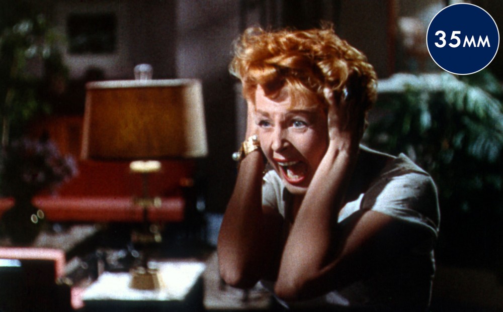 Actor Rhonda Fleming holds her hands over her ears and screams.