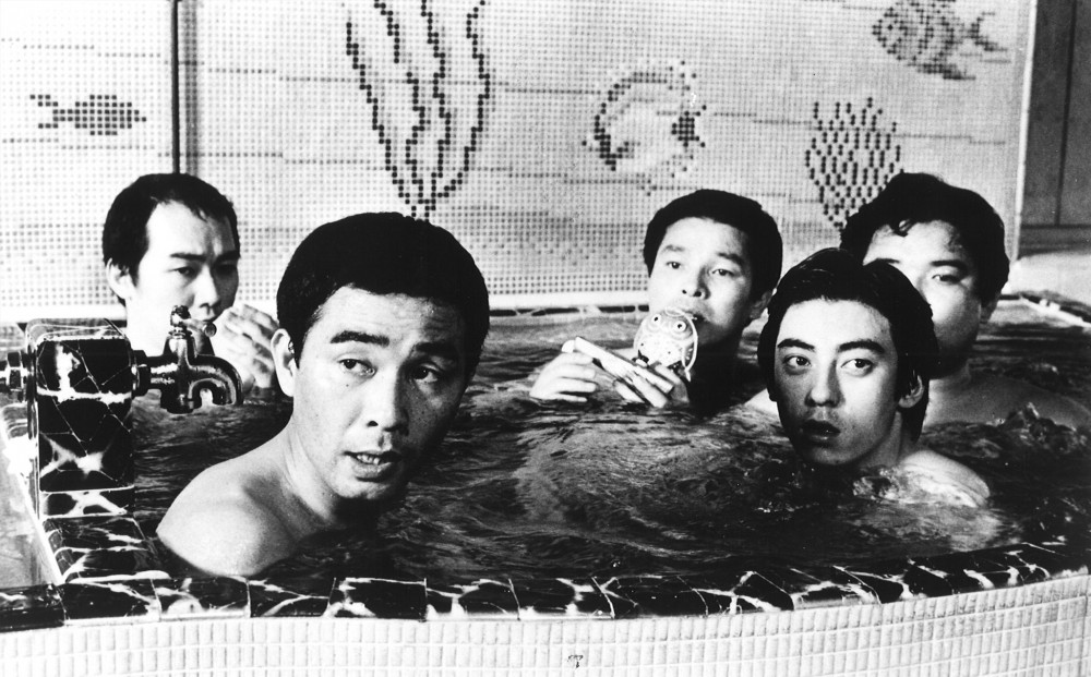Five men are in a hot tub, looking at something off-camera.