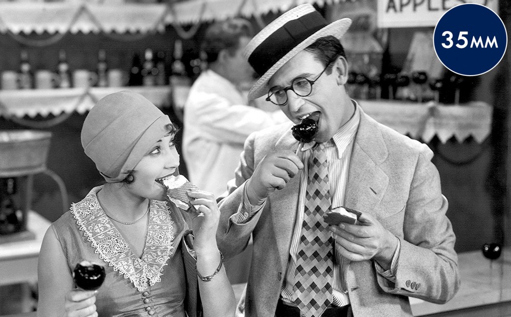 Actors Harold Lloyd and Ann Christy eat ice cream sandwiches and candy apples together.