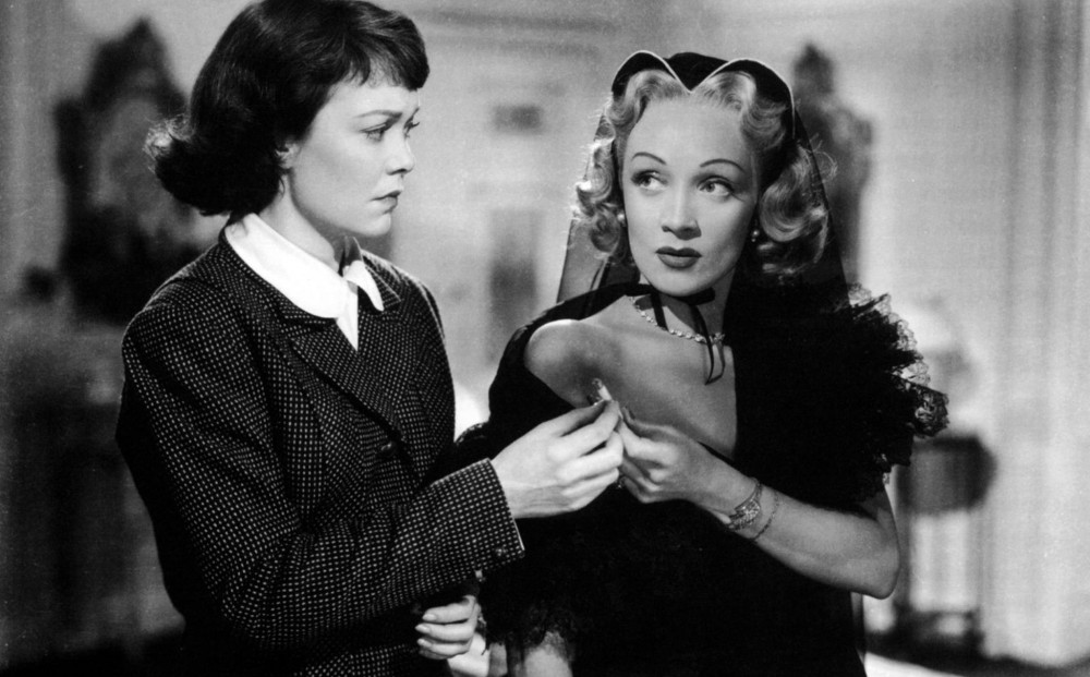 Actor Marlene Dietrich hands a lit cigarette to her servant (Jane Wyman).