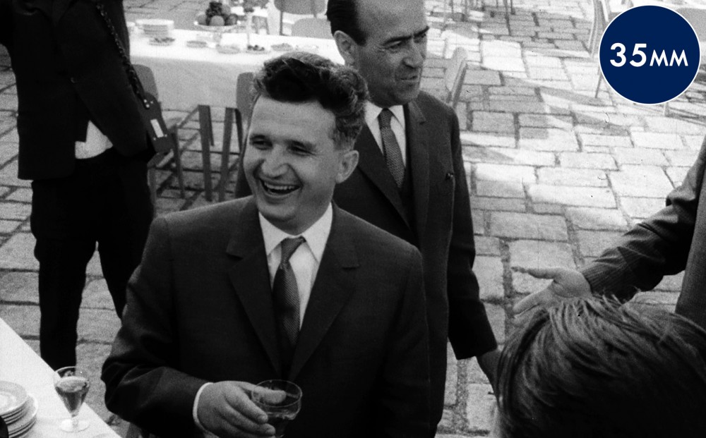 Black and white image of Romanian leader Nicolae Ceausescu smiling and holding a beverage.