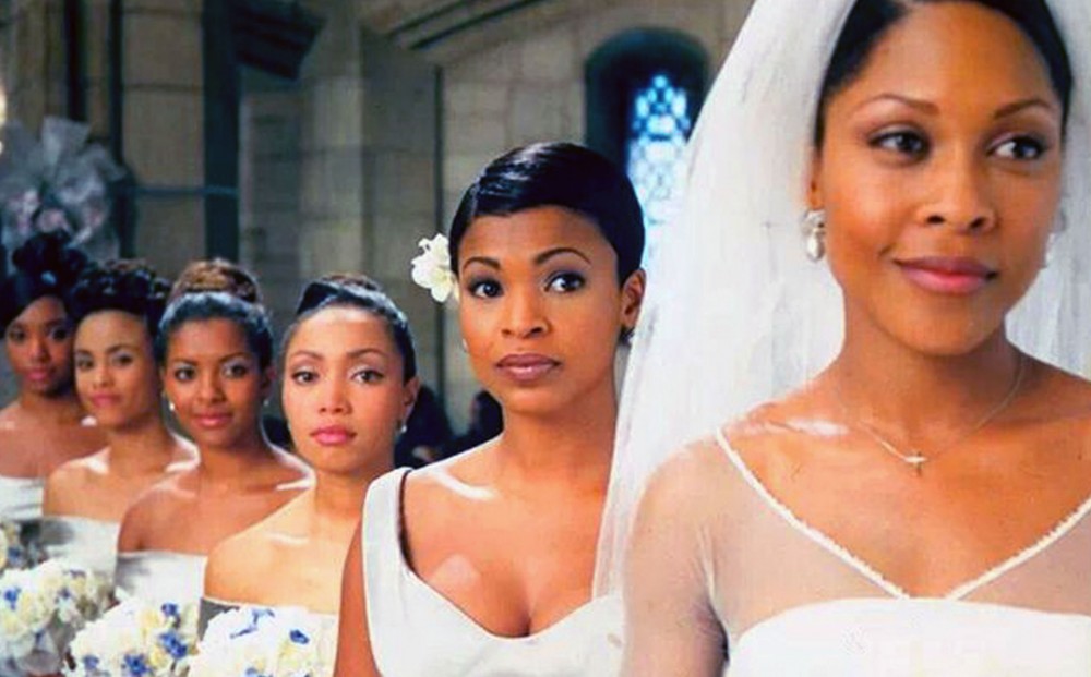 A bride stands in a church, with five bridesmaids in a row behind her.