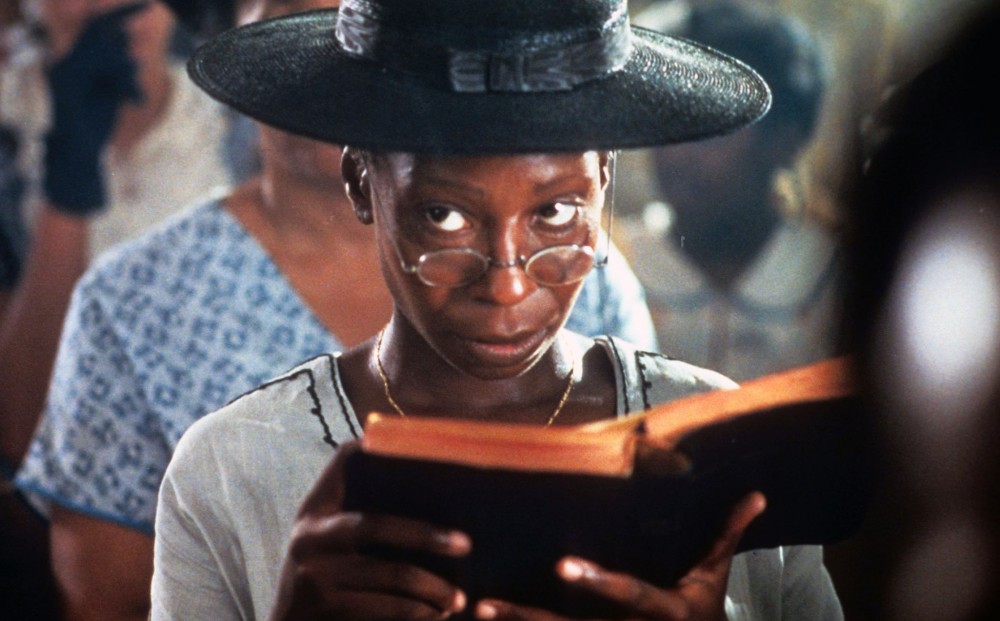 Actor Whoopi Goldberg looks up from a Bible she holds, sitting in church.