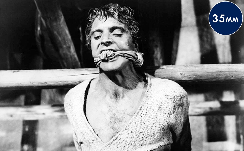 Actor Burt Lancaster is gagged with a cloth wrapped around his mouth and his hands tied together behind him.
