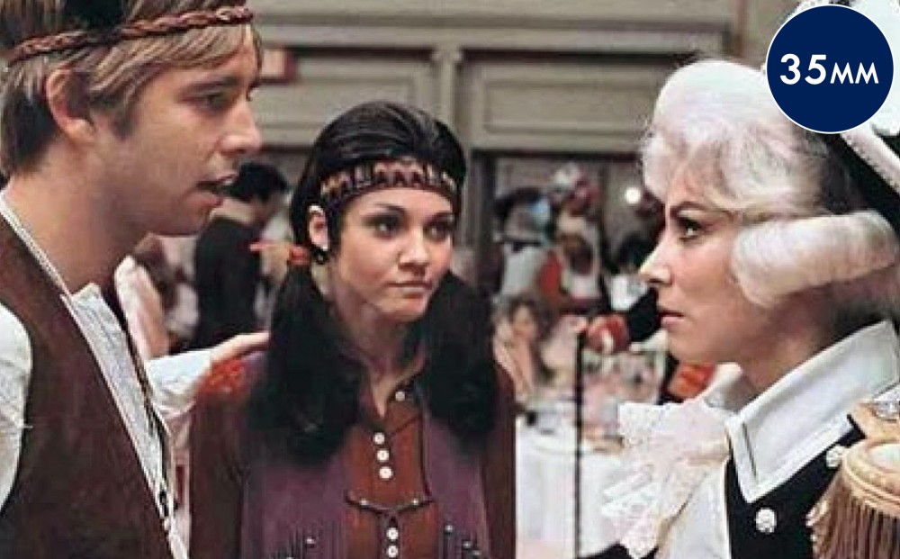 Three people costumed as two Native Americans and one Revolutionary War-era gentleman with a white wig.