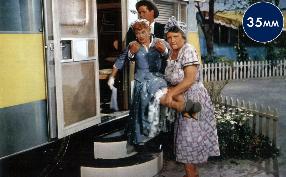 Actor Lucille Ball is being carried by two others - either into or out of the long, long trailer.
