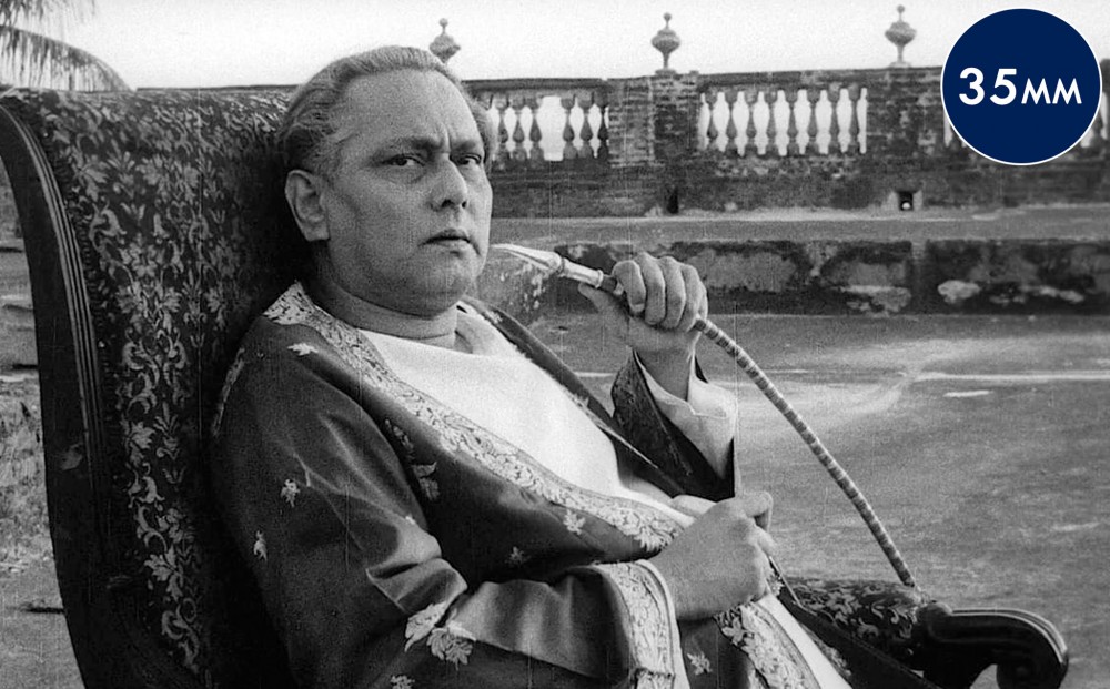 Actor Chabhhi Biswas sits on an ornate chair, smoking from a hookah pipe.