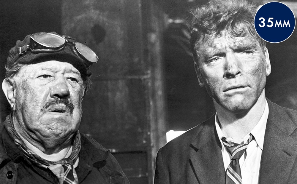 Actor Burt Lancaster stands with another man; both look dirty and ragged.