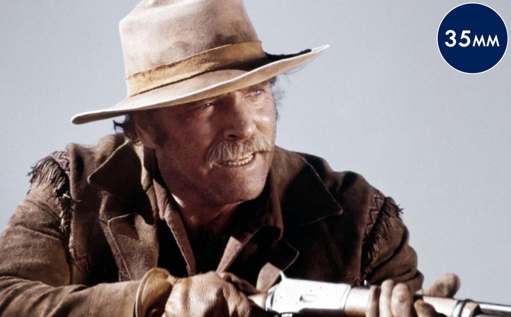 Actor Burt Lancaster, looking very dusty, holds a gun.