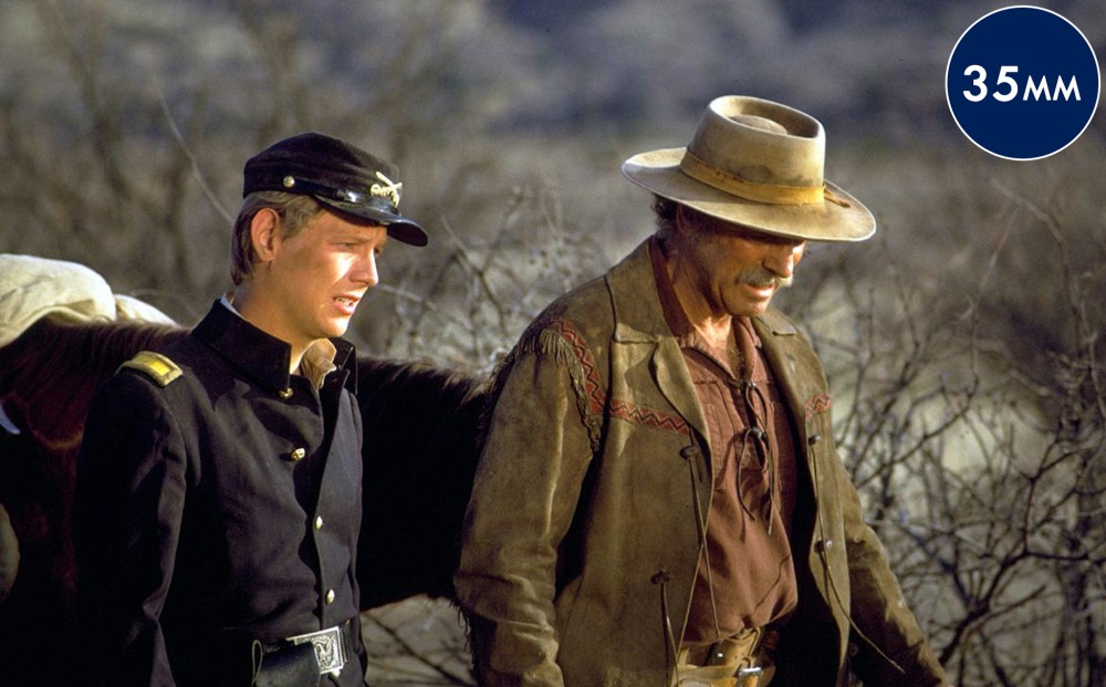 Actor Burt Lancaster walks a horse, alongside a lieutenant played by Bruce Davison.