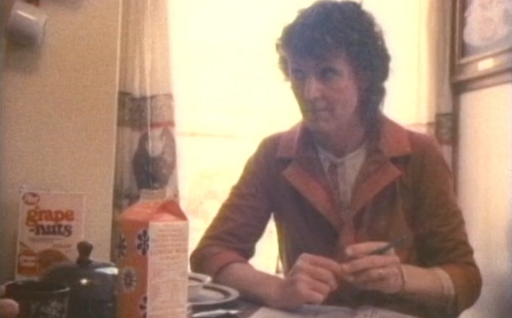 One of the film's subjects sits at a kitchen table, pen in hand.