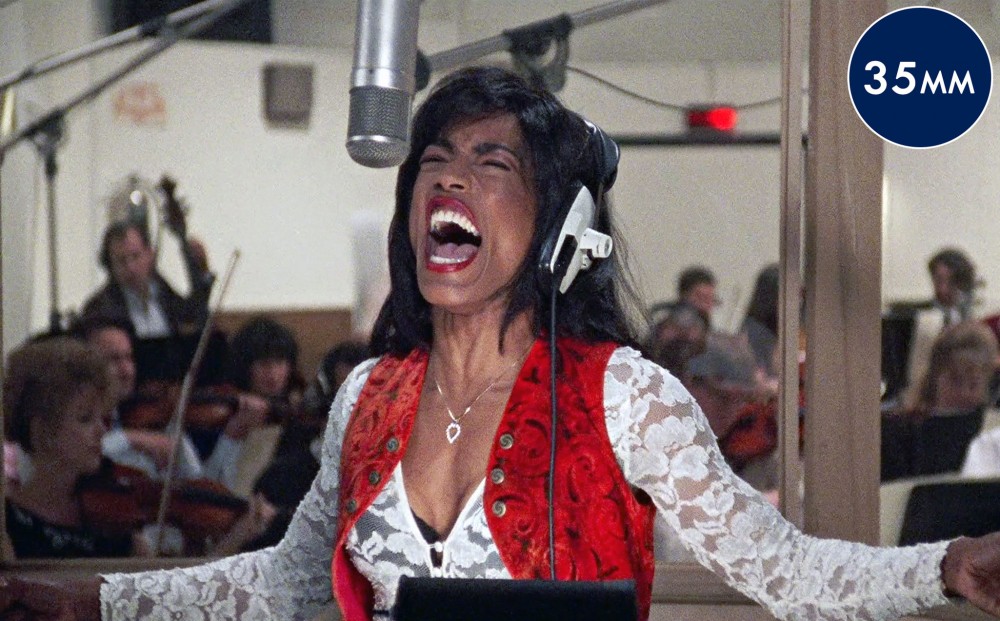 Actor Angela Bassett (as Tina Turner)  sings in a studio, surrounded by musicians.