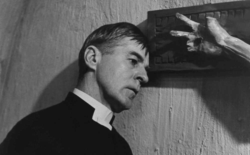 Actor Gunnar Björnstrand in his pastor's garb, leans his head against a wall.